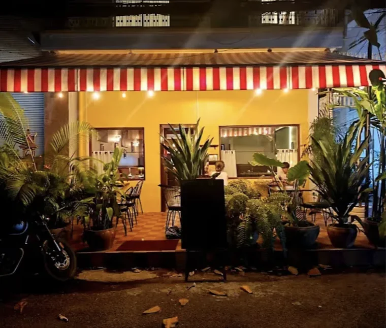 Yellow bistro front with a striped awning at night